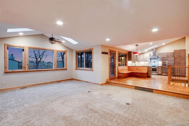 unfurnished living room with recessed lighting, lofted ceiling with skylight, and light carpet