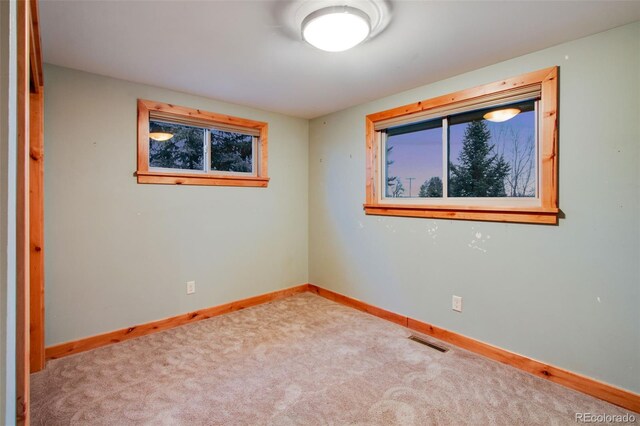 carpeted spare room featuring baseboards, visible vents, and a wealth of natural light