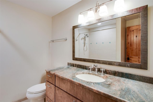 bathroom with toilet, vanity, and a tile shower