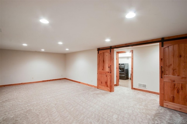 finished basement with baseboards, visible vents, recessed lighting, a barn door, and light colored carpet