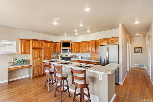 kitchen featuring a kitchen island, appliances with stainless steel finishes, a breakfast bar area, and light wood-type flooring