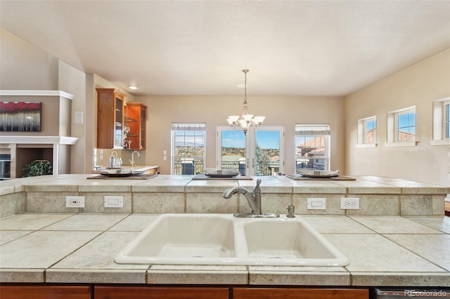 kitchen featuring a healthy amount of sunlight, sink, tile counters, and decorative light fixtures