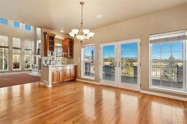 interior space with a notable chandelier, light hardwood / wood-style floors, and french doors