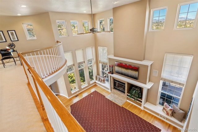 stairway with a towering ceiling, a healthy amount of sunlight, and wood-type flooring