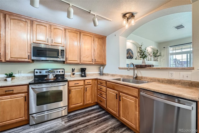 kitchen with appliances with stainless steel finishes, sink, dark wood-type flooring, and a textured ceiling