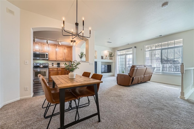 dining space with light colored carpet and a notable chandelier