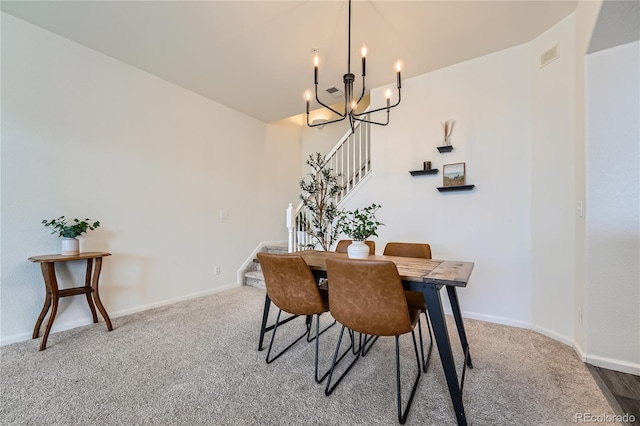 carpeted dining area with a chandelier