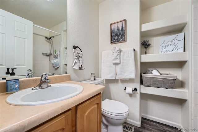 bathroom with vanity, wood-type flooring, a shower, and toilet