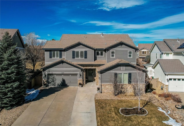 view of front of property featuring concrete driveway, stone siding, a tiled roof, an attached garage, and fence