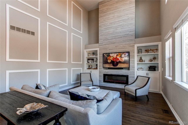 living room featuring plenty of natural light, built in shelves, a fireplace, and visible vents