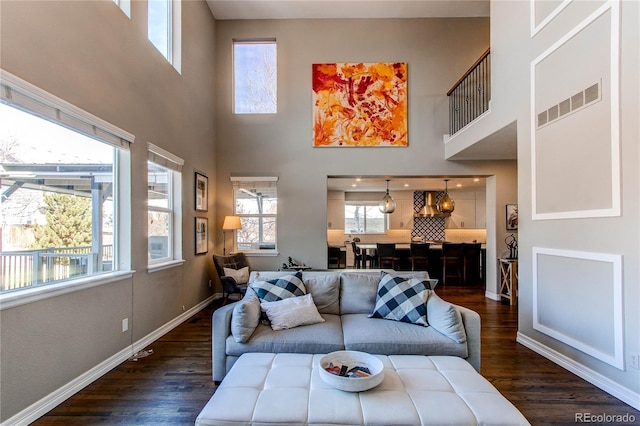 living area featuring baseboards, visible vents, and dark wood-type flooring