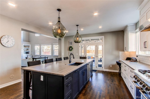 kitchen with a breakfast bar, dark wood-style flooring, a sink, white cabinetry, and light countertops