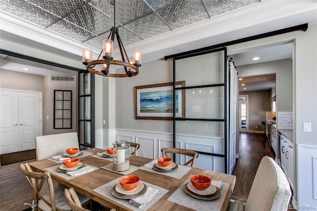 dining space featuring a notable chandelier, visible vents, wainscoting, dark wood finished floors, and an ornate ceiling