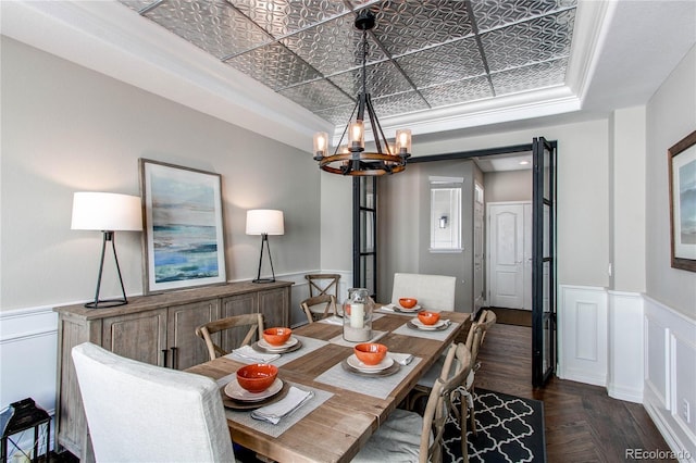 dining room with wainscoting, an ornate ceiling, ornamental molding, dark wood-type flooring, and a chandelier