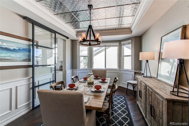 dining room featuring dark wood-style floors, an ornate ceiling, a wainscoted wall, ornamental molding, and a notable chandelier