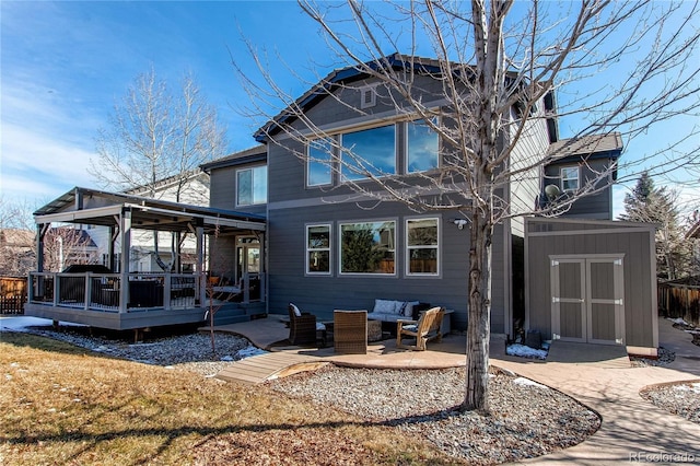 back of property featuring a wooden deck, a storage unit, an outdoor living space, and an outbuilding