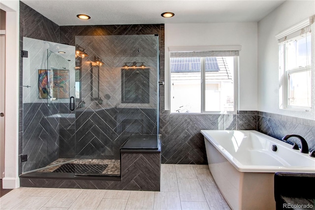 full bathroom featuring a stall shower, tile walls, and a freestanding bath