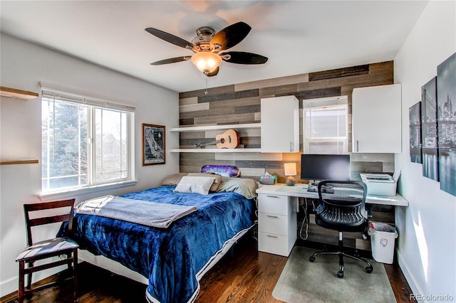 bedroom featuring a ceiling fan, wood walls, baseboards, and wood finished floors