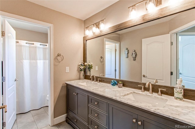 bathroom with double vanity, a sink, baseboards, and tile patterned floors