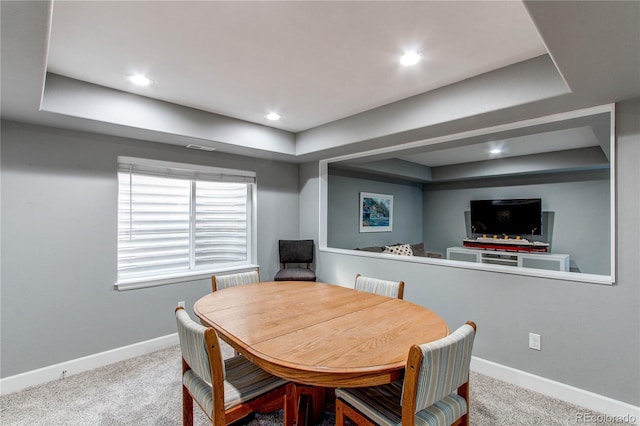 carpeted dining space with baseboards, a raised ceiling, and recessed lighting