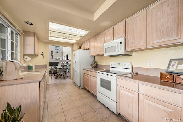 kitchen with light brown cabinets, light tile patterned floors, white appliances, and sink