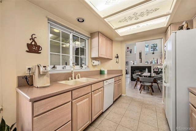 kitchen featuring light brown cabinets, light tile patterned flooring, white appliances, and sink