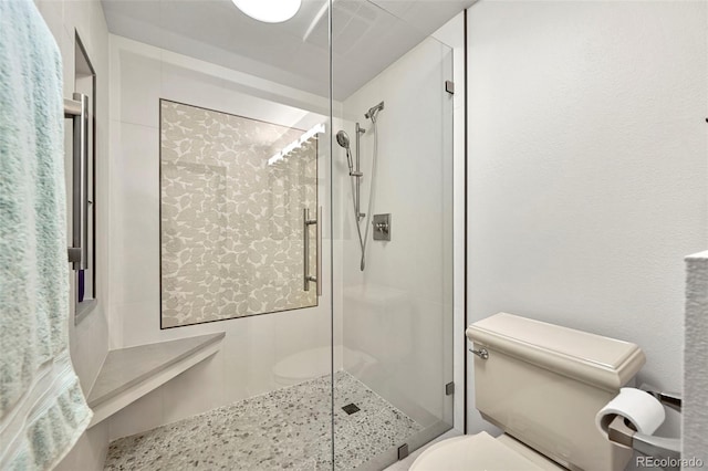 bathroom featuring a shower with shower door and toilet