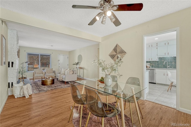 dining room featuring sink, light hardwood / wood-style flooring, a textured ceiling, and ceiling fan