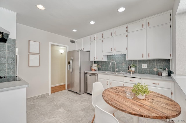 kitchen featuring appliances with stainless steel finishes, white cabinetry, sink, backsplash, and light tile patterned floors