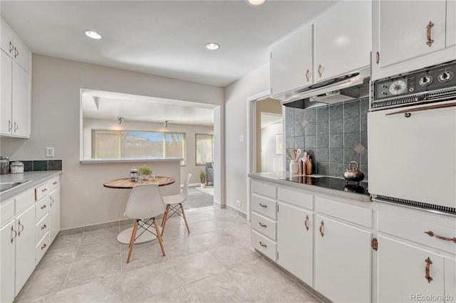 kitchen with white cabinetry, oven, black electric cooktop, and decorative backsplash