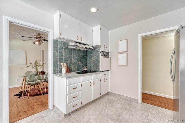 kitchen featuring stainless steel fridge, white cabinetry, backsplash, black electric stovetop, and oven