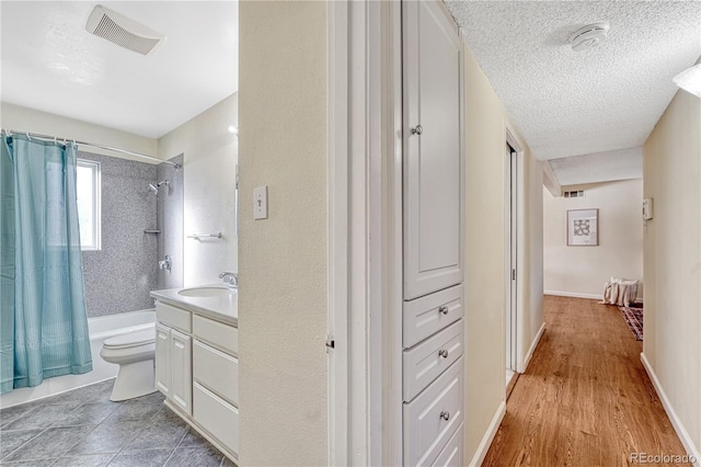 full bathroom featuring toilet, vanity, shower / bathtub combination with curtain, and a textured ceiling