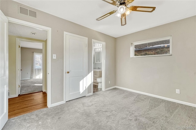 unfurnished bedroom with ceiling fan, light carpet, and ensuite bath