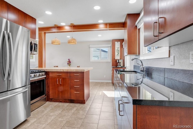 kitchen with sink, kitchen peninsula, stainless steel appliances, pendant lighting, and decorative backsplash