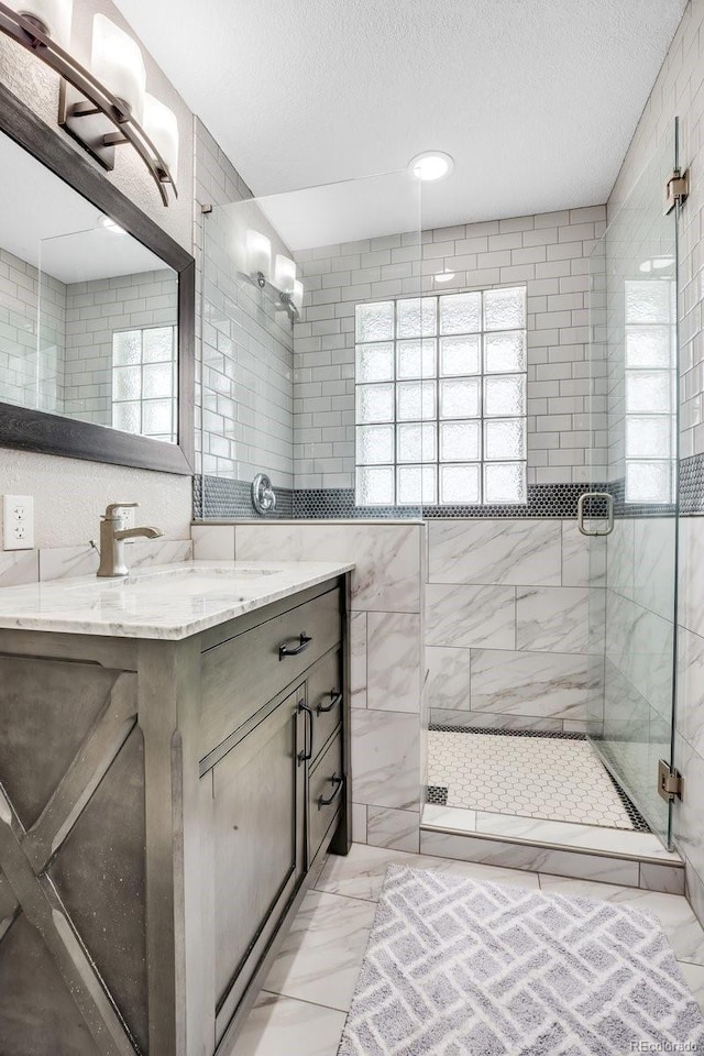 bathroom with vanity, a healthy amount of sunlight, walk in shower, and a textured ceiling