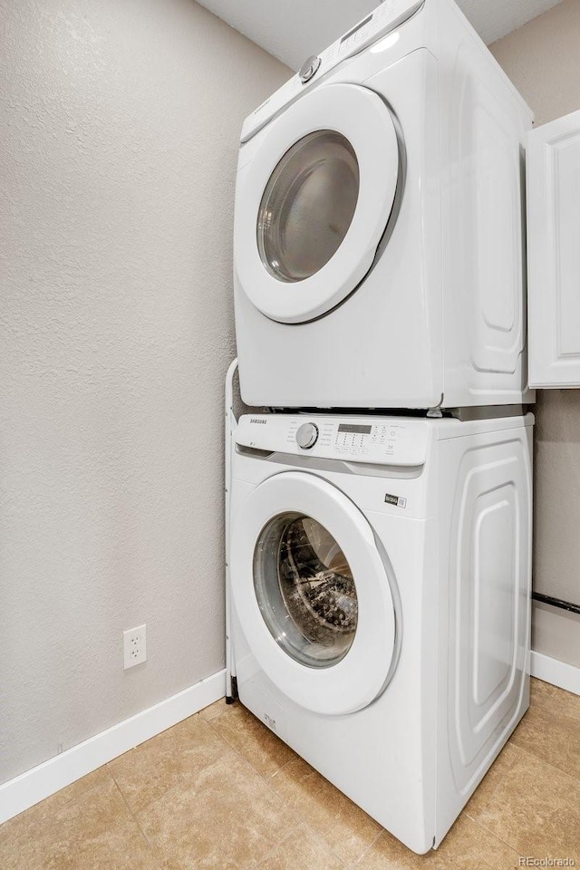 washroom featuring stacked washer / dryer and light tile patterned floors