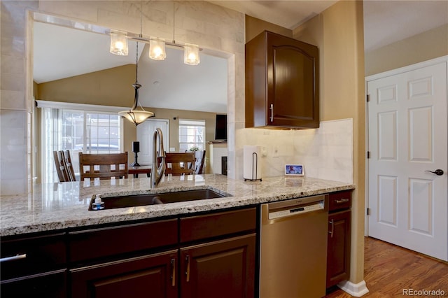 kitchen featuring backsplash, light stone countertops, dishwasher, wood finished floors, and a sink