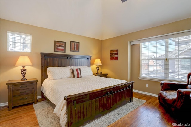 bedroom featuring multiple windows, light wood-style floors, and baseboards