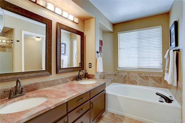 bathroom featuring a bath, double vanity, and a sink