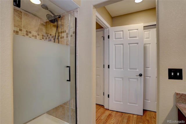 full bathroom with wood finished floors, a stall shower, and vanity