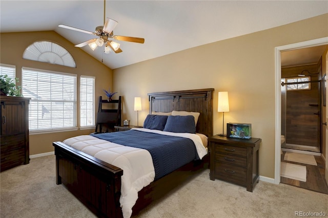 carpeted bedroom featuring baseboards, lofted ceiling, ensuite bathroom, and a ceiling fan