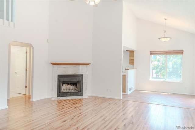 7978 S Johnson Ct, Littleton, CO 80128 - unfurnished living room with high vaulted ceiling, wood finished floors, a fireplace with flush hearth, and arched walkways