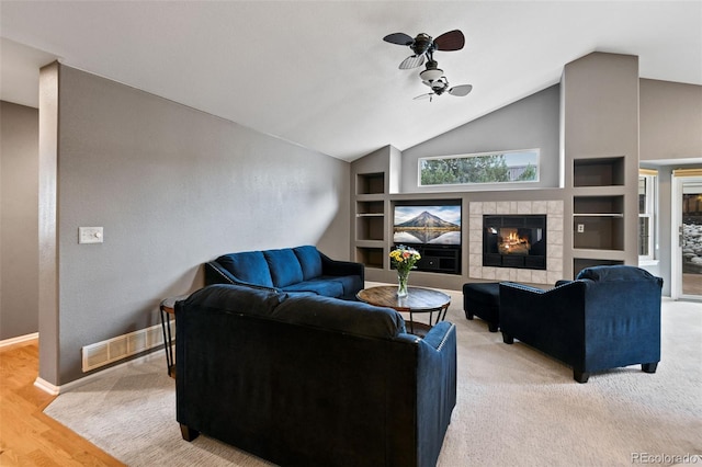 8829 S Dudley St, Littleton, CO 80128 - living room featuring a ceiling fan, lofted ceiling, a tiled fireplace, built in features, and light wood-style floors