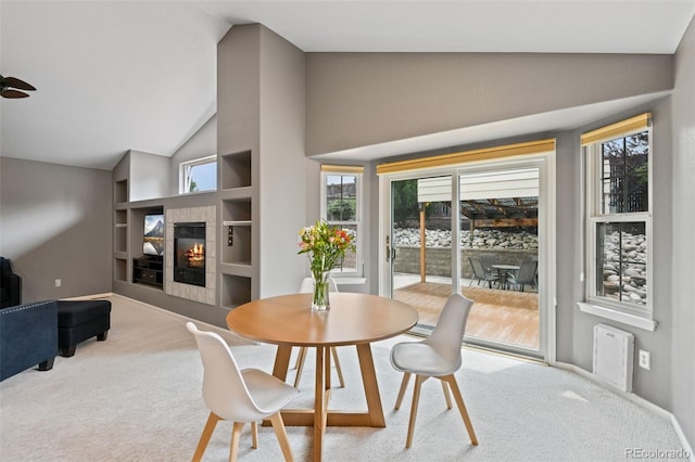 8829 S Dudley St, Littleton, CO 80128 - carpeted dining area featuring a fireplace, healthy amount of natural light, built in shelves, a ceiling fan, and high vaulted ceiling