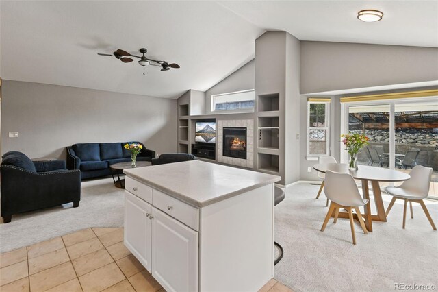 8829 S Dudley St, Littleton, CO 80128 - kitchen with light carpet, white cabinetry, built in features, a tiled fireplace, and open floor plan