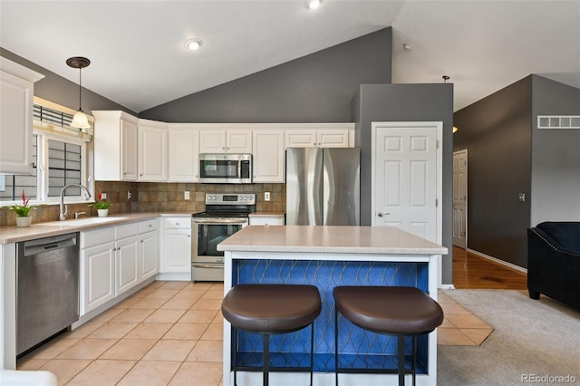 8829 S Dudley St, Littleton, CO 80128 - kitchen with appliances with stainless steel finishes, white cabinetry, a kitchen island, tasteful backsplash, and hanging light fixtures