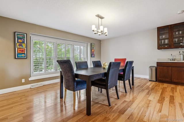 6062 S Emporia Cir, Englewood, CO 80111 - dining area with visible vents, baseboards, a notable chandelier, light wood-style floors, and bar area