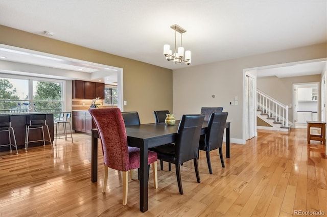 6062 S Emporia Cir, Englewood, CO 80111 - dining area with baseboards, stairs, light wood-style flooring, and a notable chandelier