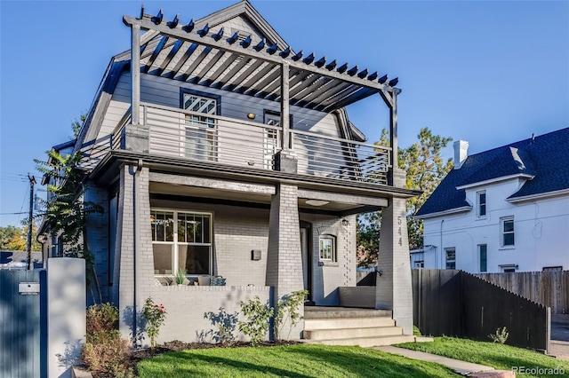 view of front of home with a pergola, a balcony, and a front lawn