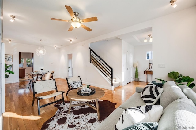 living room with a healthy amount of sunlight, ceiling fan with notable chandelier, and light wood-type flooring